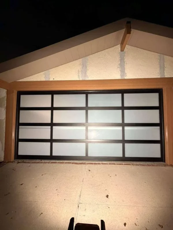 Black full-view glass garage door installed by Right Choice Garage Door at night