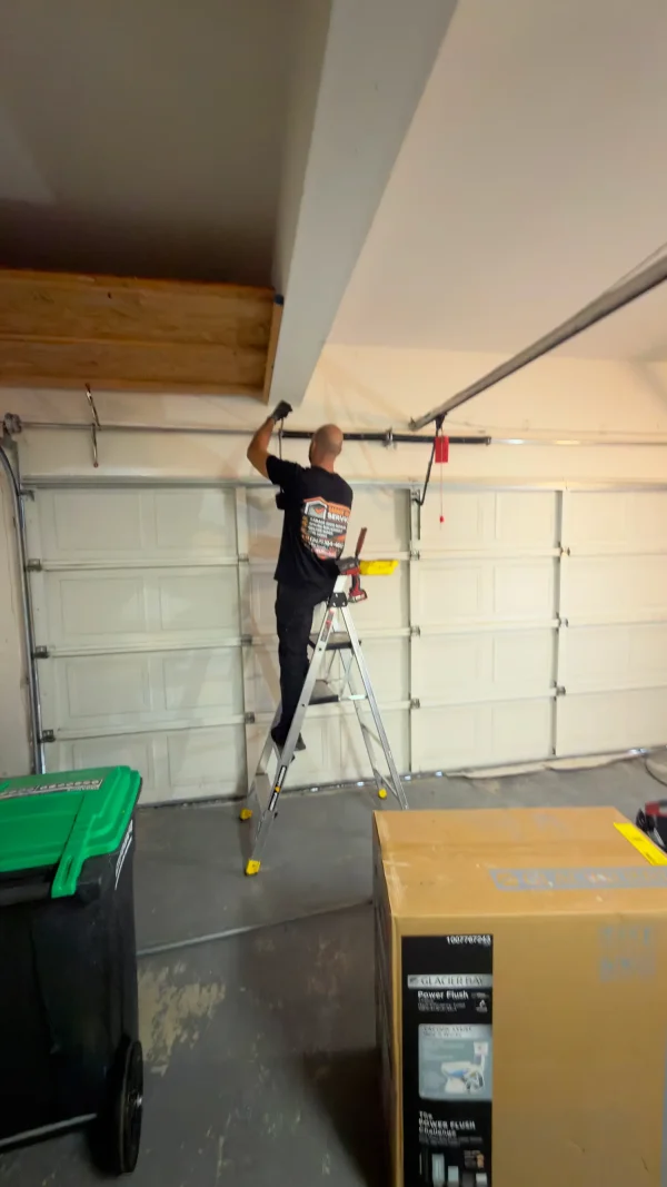 Right Choice technician on a ladder servicing a garage door track and torsion spring shaft